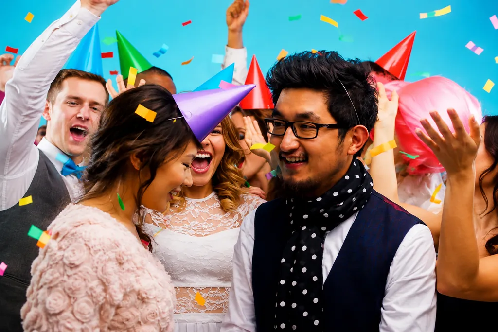 Friends in party hats celebrating under falling confetti