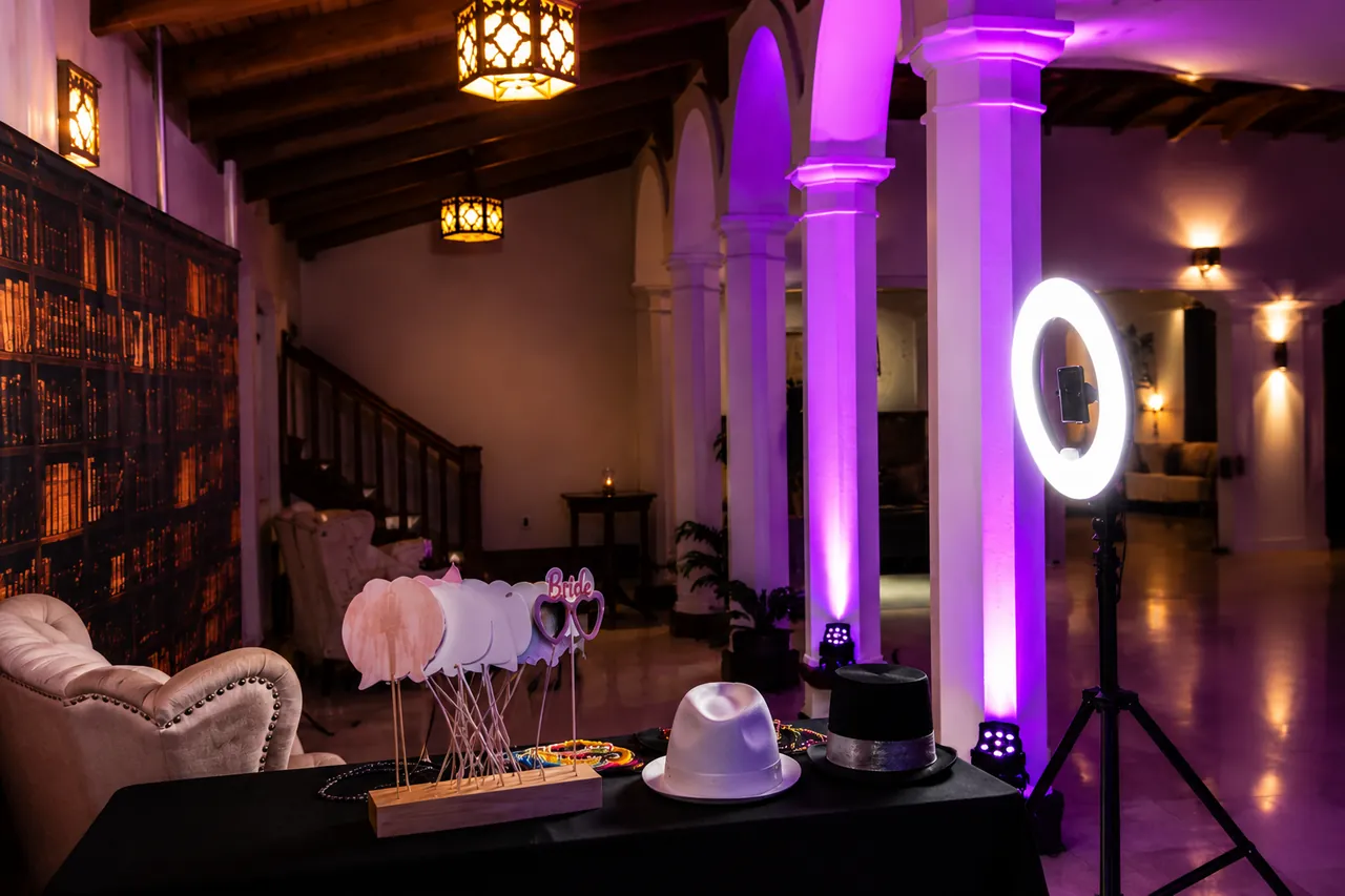 A ring-light booth and props table set up in a purple-lit hall
