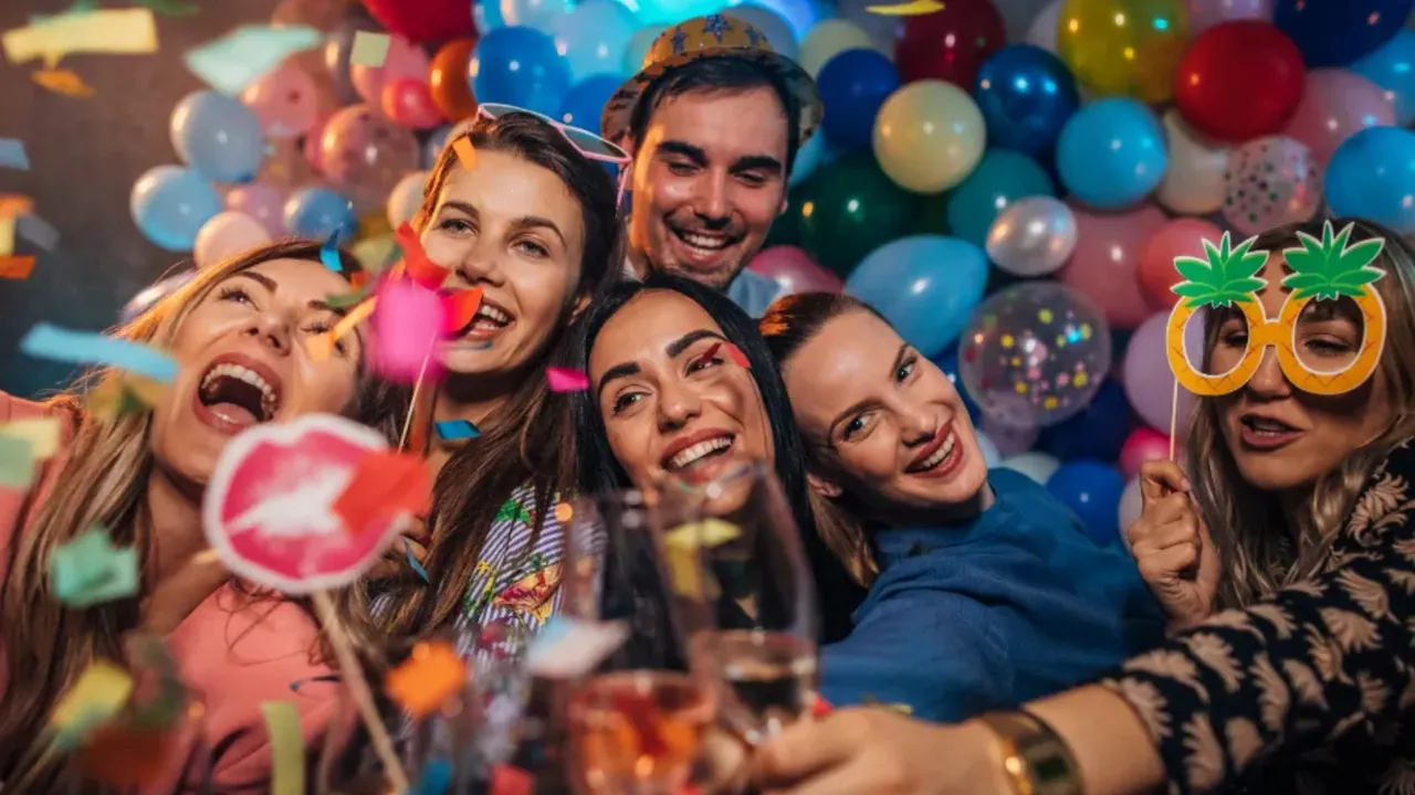 Friends squeezing into a photo with props in front of balloons