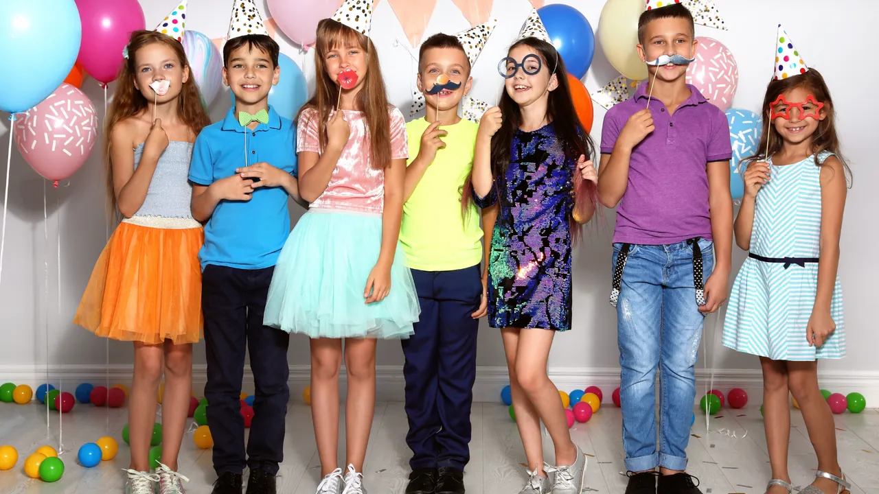 A group of kids with props at an open-air photo booth
