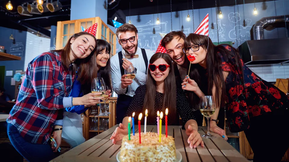 Friends celebrating around a birthday cake with candles