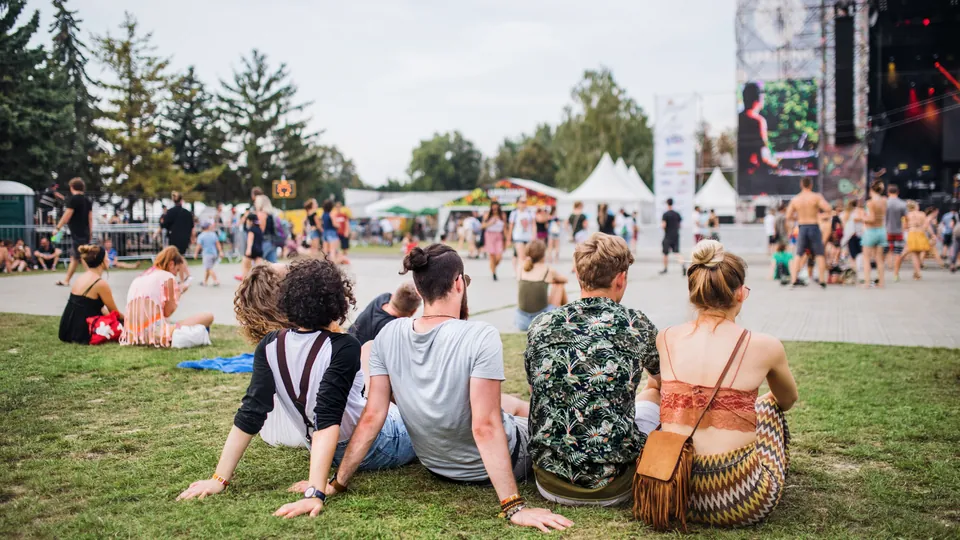 Festival-goers relaxing on the lawn in front of a stage