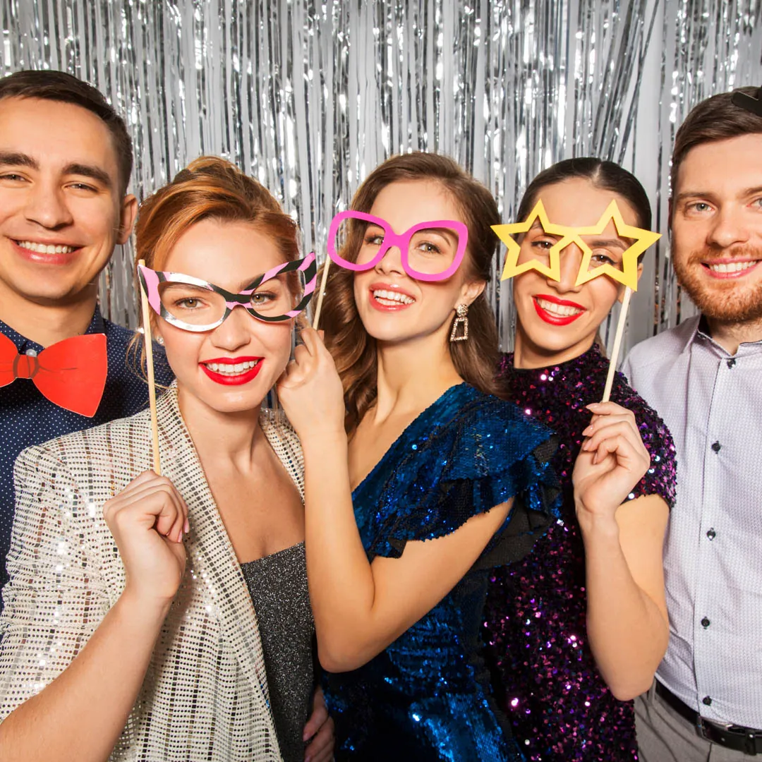 Friends posing with glasses and star props in front of a silver backdrop