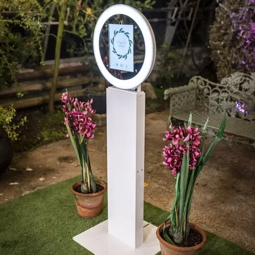 The white social booth kiosk with its ring light, set up in a garden