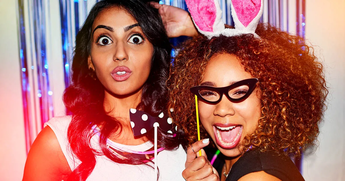Two guests posing with glasses and bunny-ear props